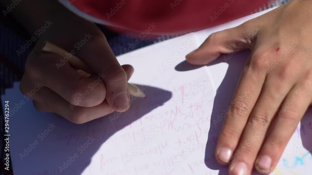 Close-up of a child hand while write a letter in sunlight Close-up of a child hand while write a letter in sunlight