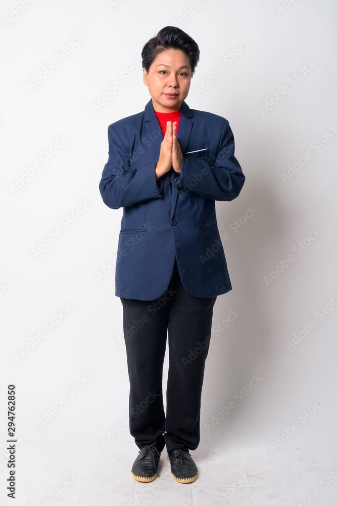 Full body shot of mature Asian businesswoman with Wai as Thai greeting Full body shot of mature Asian businesswoman with Wai as Thai greeting