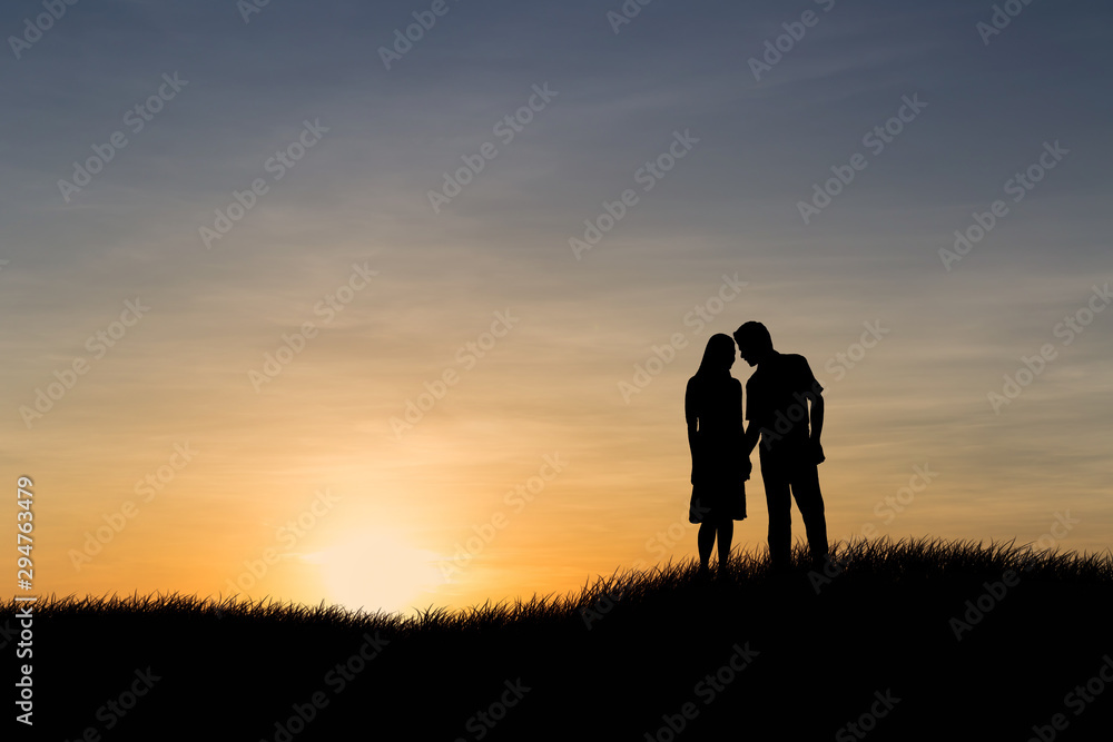 Silhouettes of couple man and woman in nature sunset background. Love concept.
