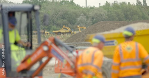 Large Industrial Crane Vehicle and Workmen on Construction Site. Digger Moving Quarry Earth in Britain.