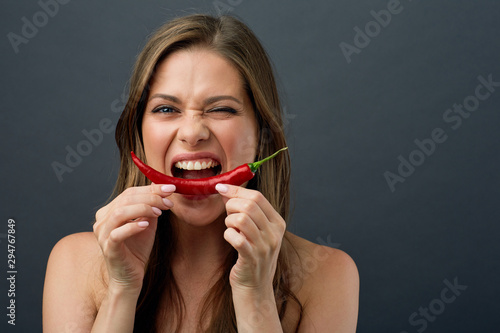 woman with naked shoulders eating red hot chilli peppers.