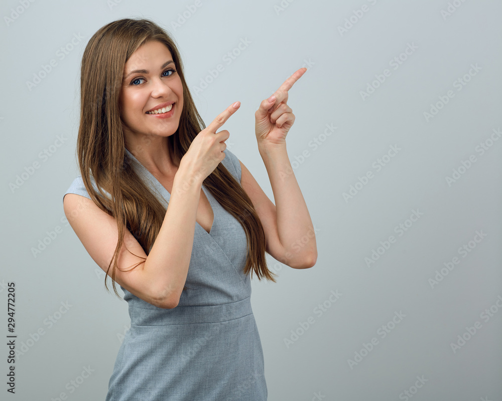 Smiling woman in gray dress pointing with two fingers. Smiling woman in gray dress pointing with two fingers.