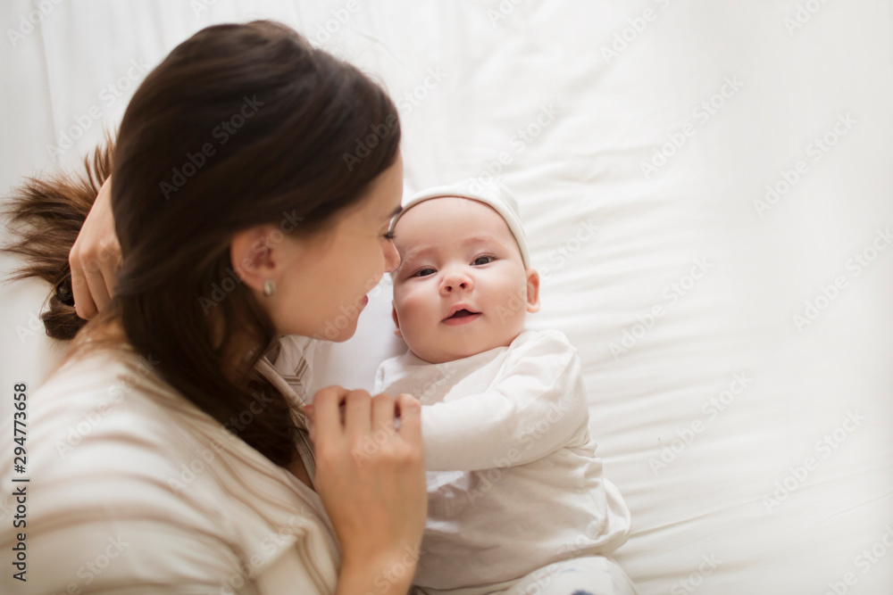 Happy mother and baby child lying on bed together Happy mother and baby child lying on bed together