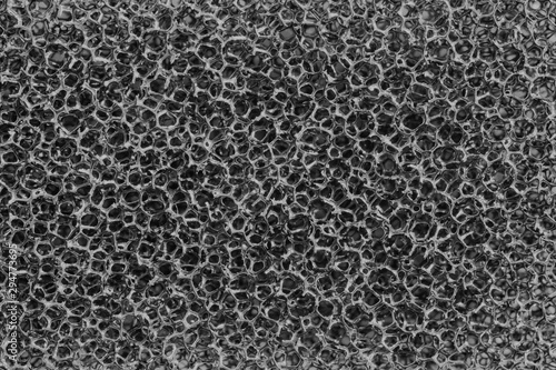 The surface texture of a black sponge for washing and wet cleaning of plastic strands, abstract background