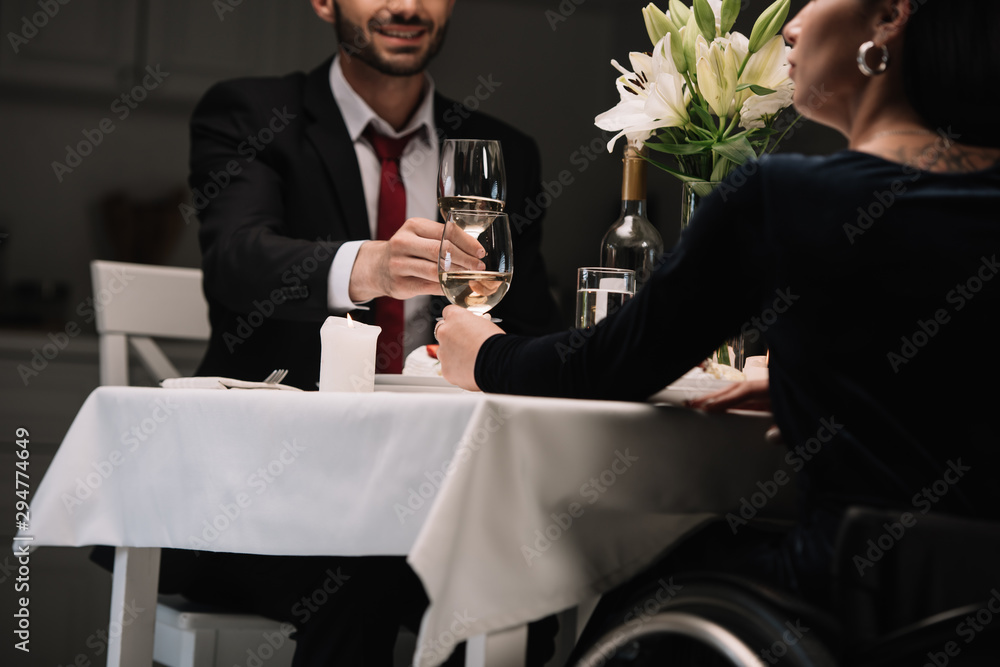 cropped view of disabled young woman clinking glasses of red wine smiling boyfriend during romantic dinner cropped view of disabled young woman clinking glasses of red wine smiling boyfriend during romantic dinner