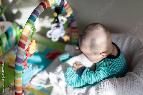 Cute baby sitting on a chair in front of colorful rainbow toys photo