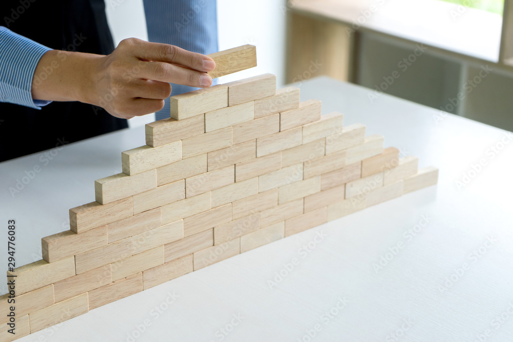 Young businessman try to build wall and tower from wooden Young businessman try to build wall and tower from wooden