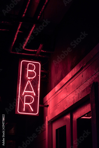 neon BAR sign lights up the doorway of a drinking establishment