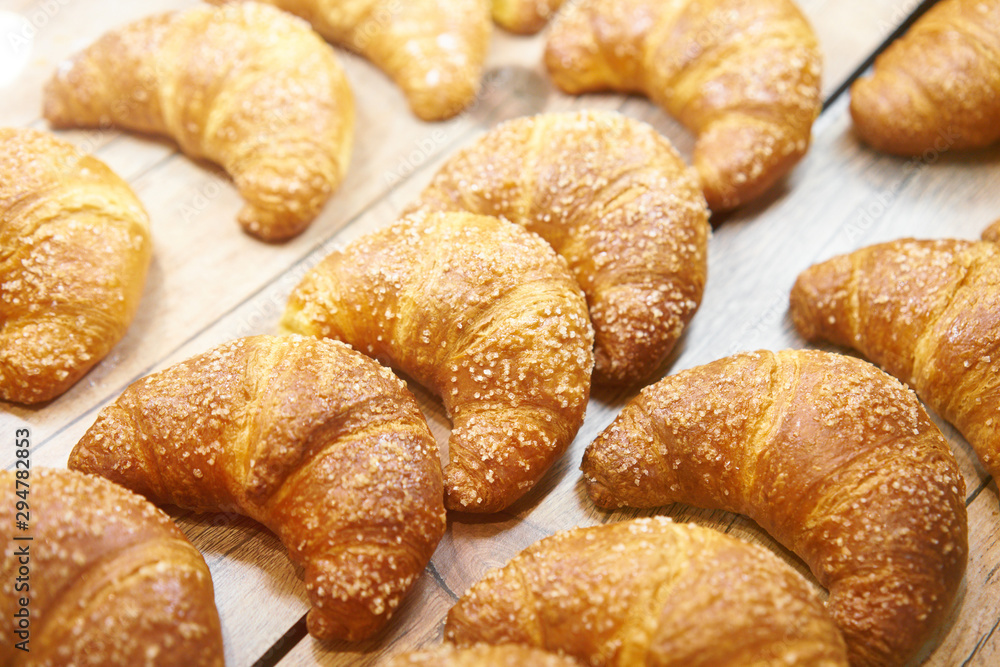 Fresh baked croissant pastry on sale in cafe. Buy tasty bakery product for coffee break. Sweet dessert food.