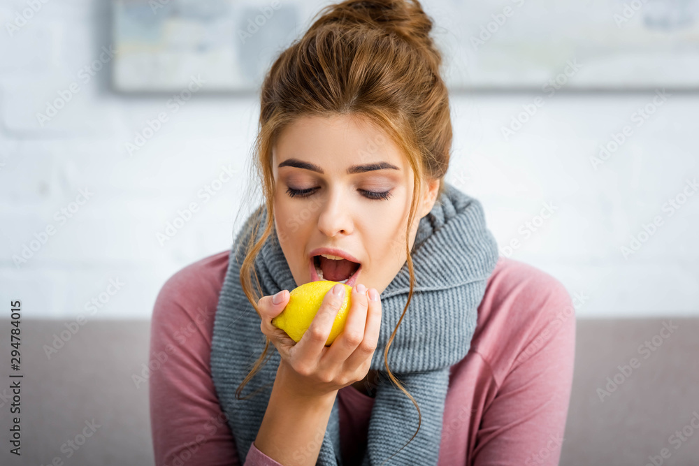 attractive and ill woman with grey scarf eating yellow lemon attractive and ill woman with grey scarf eating yellow lemon