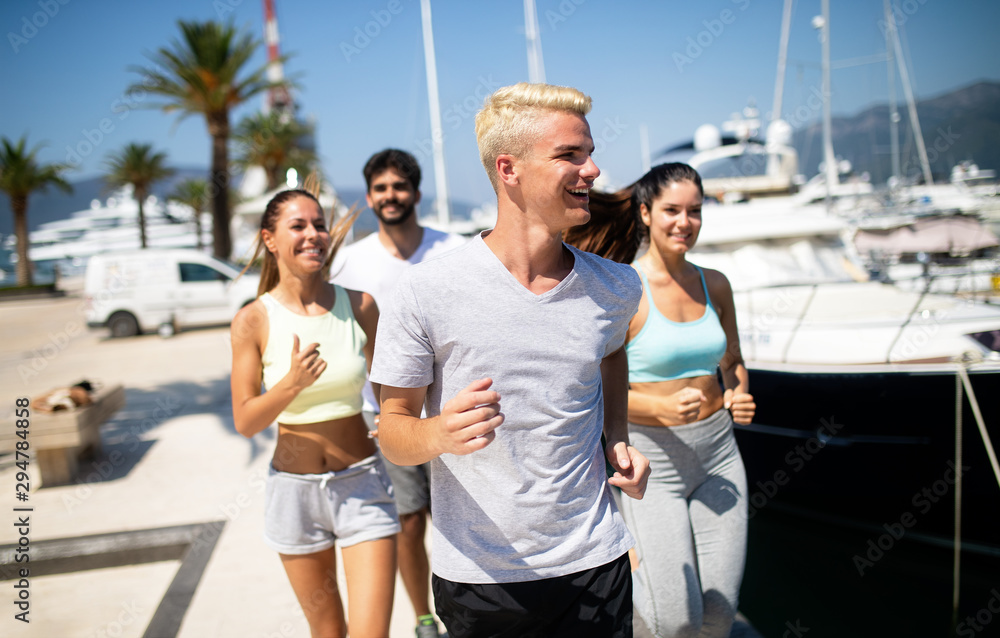 Happy fit people running and jogging together in summer sunny nature
