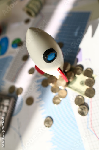 Focus on important white space ship standing on pile of golden coins and graphs and charts sheets scattered all over office workplace to analyze profitable income. Reports sale concept © H_Ko