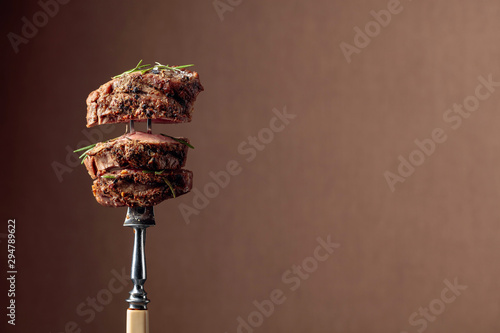 Grilled ribeye beef steak with rosemary on a brown background.