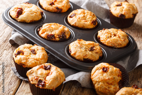 Mediterranean muffins with sun-dried tomatoes and cheddar cheese close-up in a baking dish. horizontal