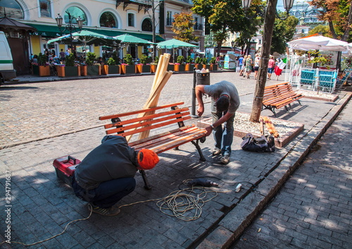 Men are repairing a bench in the city center
