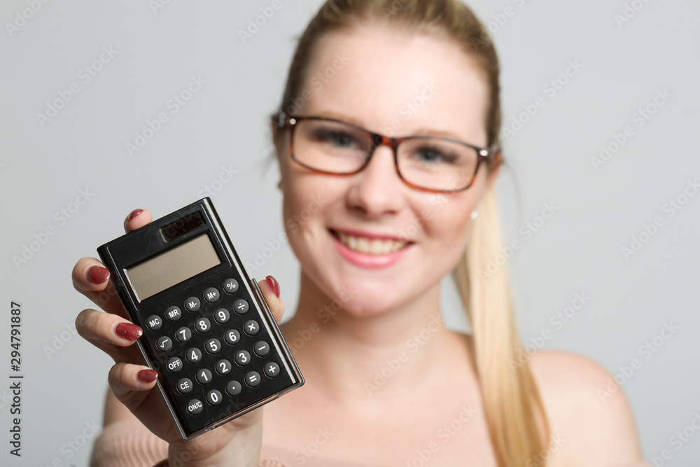 smiling woman with glasses holds a calculator in her hand smiling woman with glasses holds a calculator in her hand