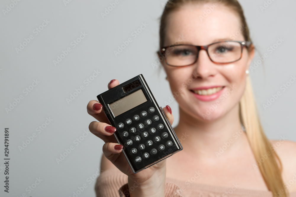 woman with glasses holds a calculator in her hand woman with glasses holds a calculator in her hand