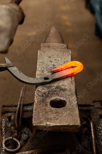 Hot metal hook tapping into final stage on factory anvil.