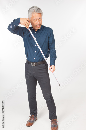 Hombre de mediana edad de origén japonés con un metro en la mano, tomando medidas; ingeniero o arquitecto o profesional preparando medidas para realizar una obra. photo