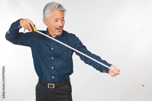Hombre de mediana edad de origén japonés con un metro en la mano, tomando medidas; ingeniero o arquitecto o profesional preparando medidas para realizar una obra. photo