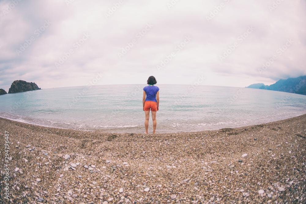 A woman walks alone on the sea coast.
