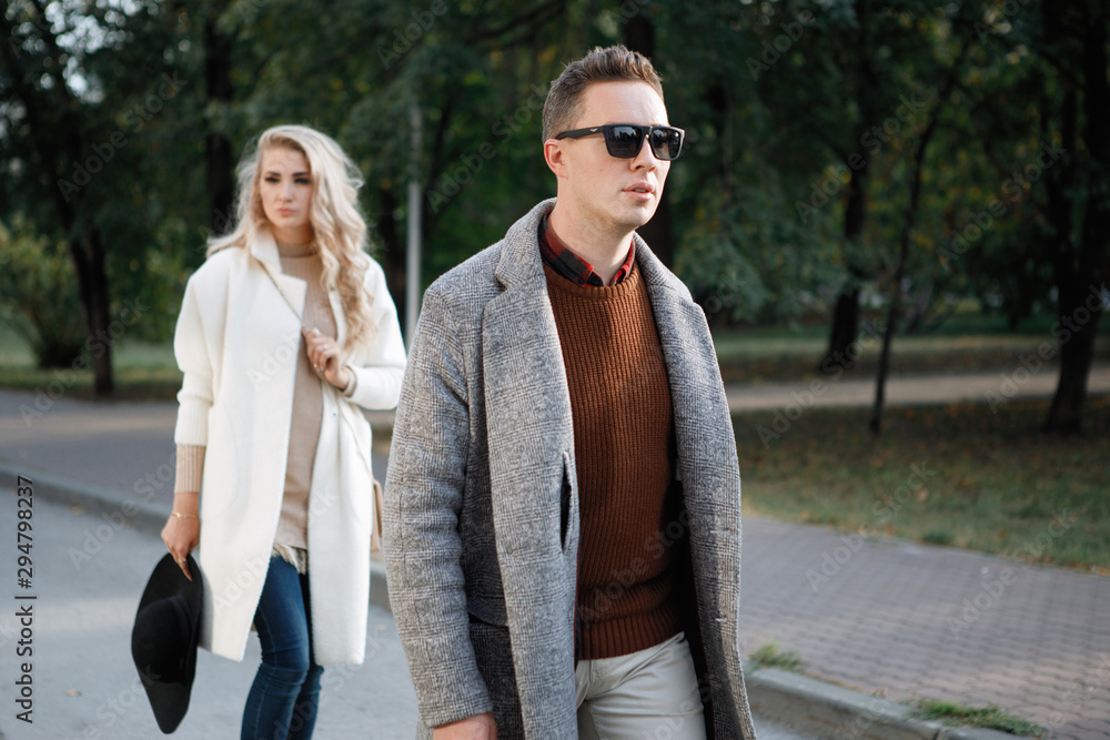 Two stylish, man and woman are walking on the street.