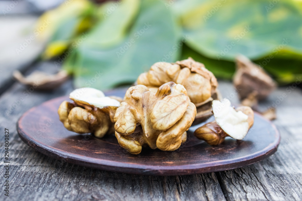 Walnuts and walnut kernels lie on a bowl on a rustic old wooden table. Walnut kernels. Walnuts and walnut kernels lie on a bowl on a rustic old wooden table. Walnut kernels.