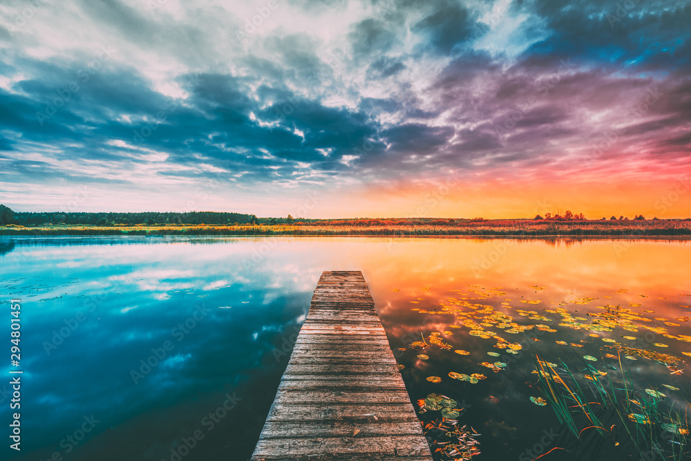 Landscape With Wooden Boards Pier On Calm Water Of Lake, River At Sunset Time, Forest On Other Side. Summer To Autumn Season Transition Concept In Nature - obrazy, fototapety, plakaty 