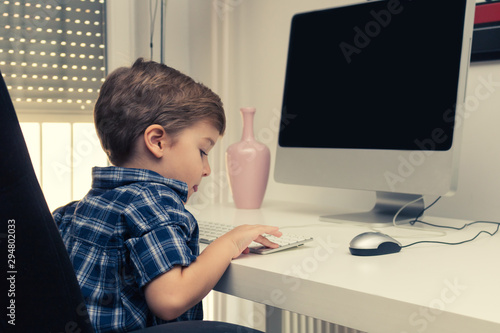 Cute kid learning to use desktop PC in the office.