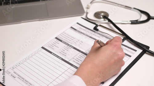 Female doctor fills a patient's medical history. Close up