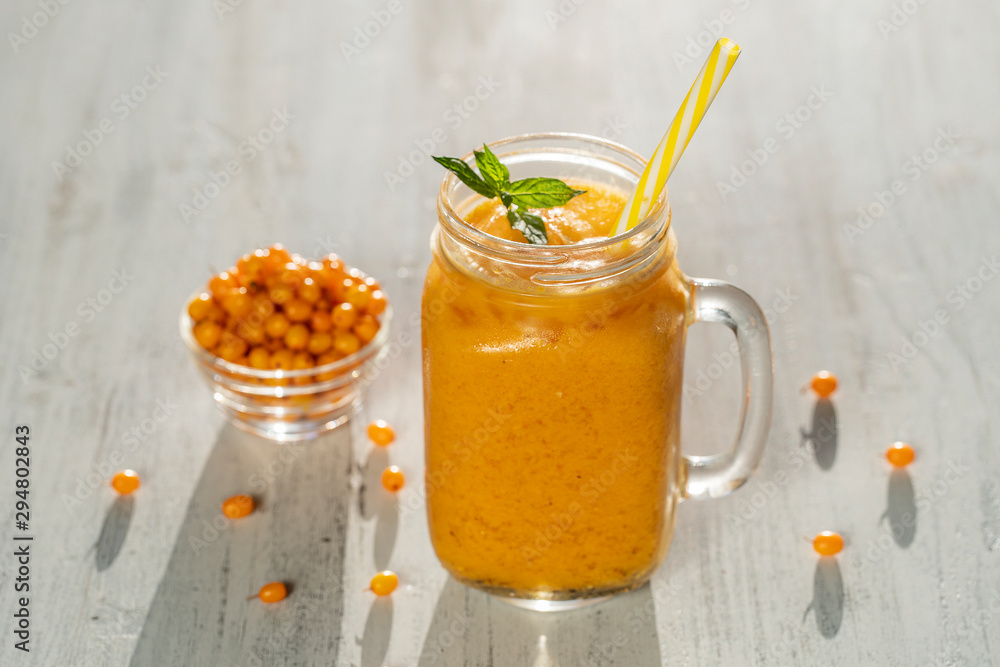 Fresh organic yellow smoothie in glass mug on white wooden table, close up. Refreshing summer fruit drink. The concept of healthy eating. Sea buckthorn smoothie Fresh organic yellow smoothie in glass mug on white wooden table, close up. Refreshing summer fruit drink. The concept of healthy eating. Sea buckthorn smoothie