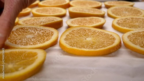 Hand lay orange slices on baking paper. Close up. 