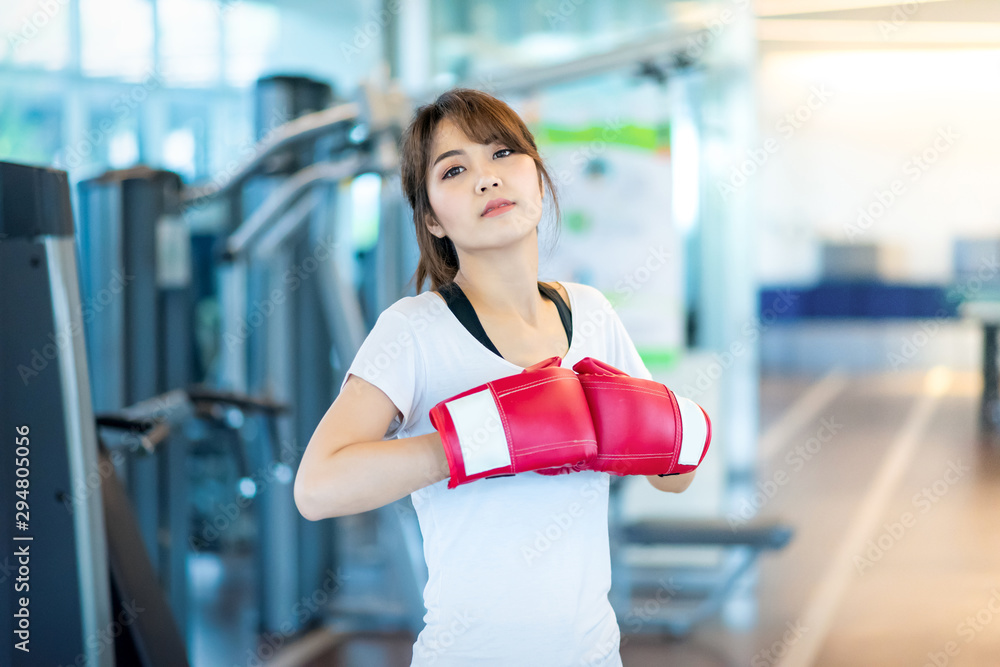 Happy attractive asian woman boxer wearing Red boxing gloves in sport fitness gym