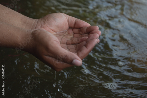 Water in male hand with surface river. World water or Environment day. Save water concept,