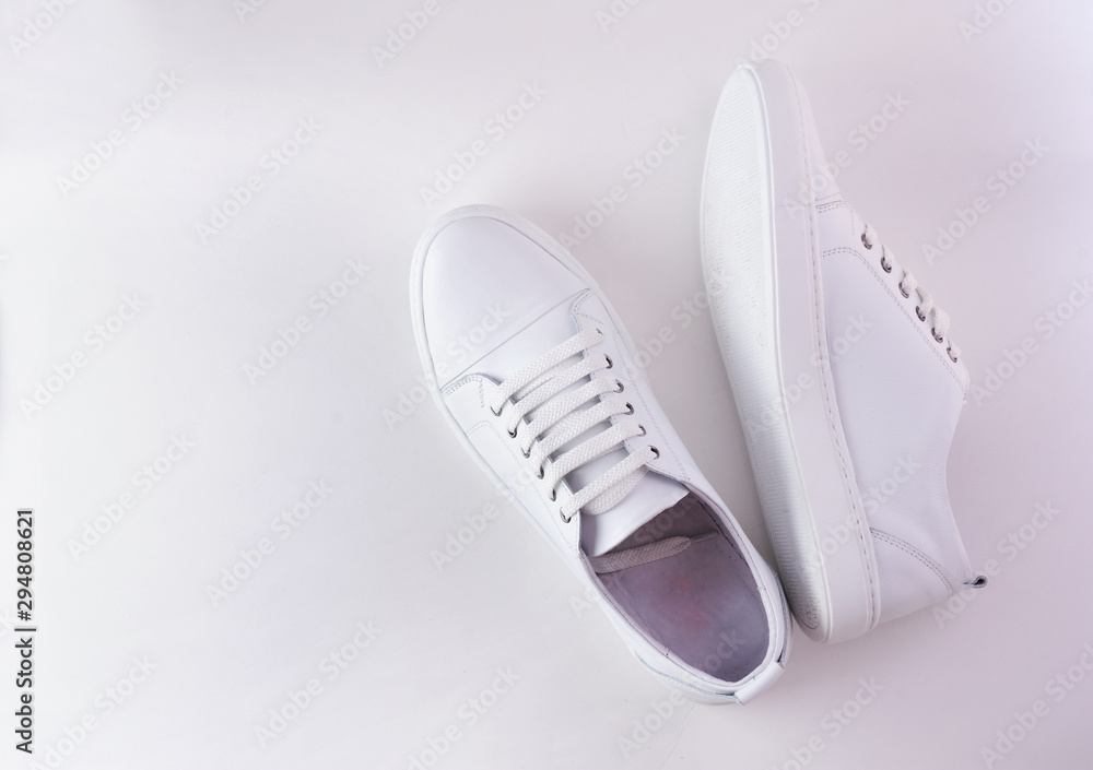 White leather sneakers on white background. Pair of fashion trendy white sport shoes or sneakers with copy space for text or design. Overhead shot of new white sneakers, monochrome.Top view or flat la White leather sneakers on white background. Pair of fashion trendy white sport shoes or sneakers with copy space for text or design. Overhead shot of new white sneakers, monochrome.Top view or flat la