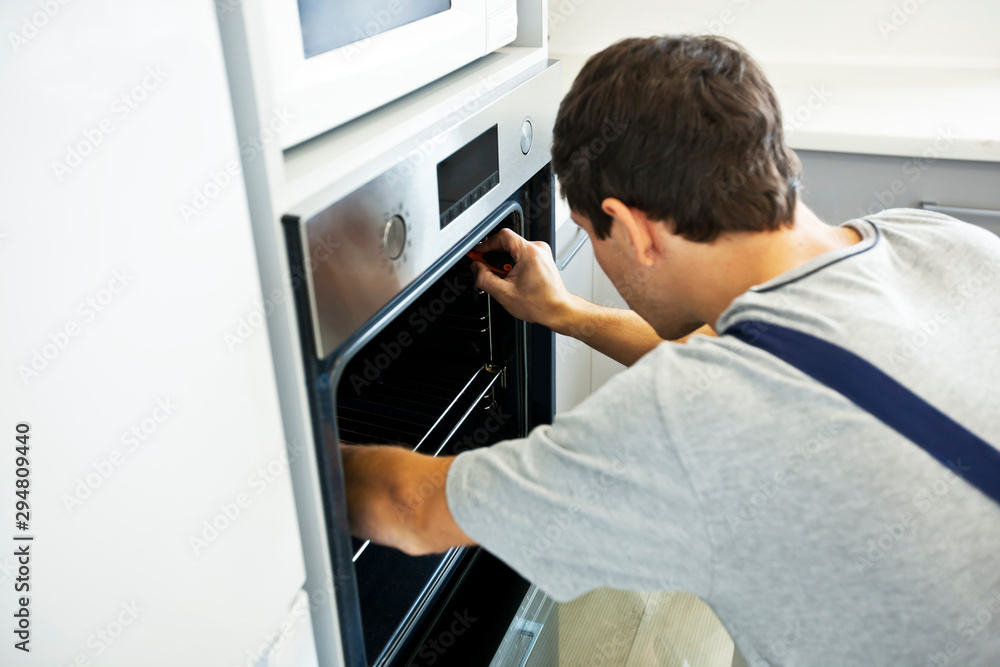 The repairer is fixing the electric oven The repairer is fixing the electric oven