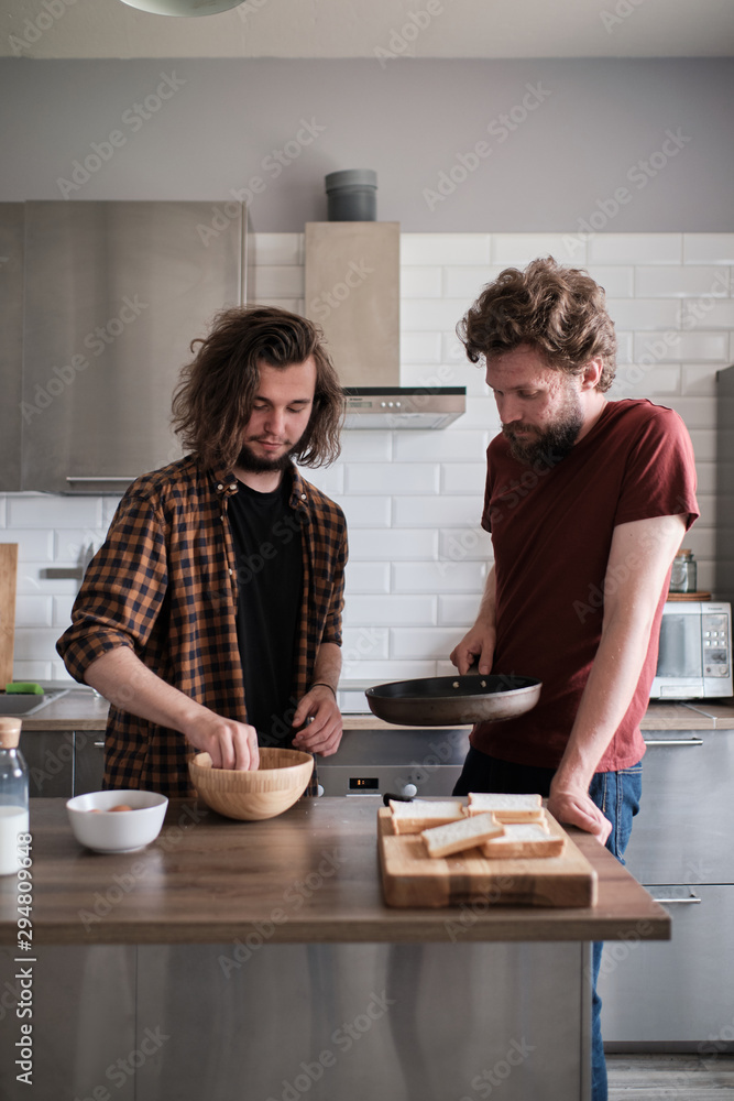 Two men cooking breakfast in the kitchen. Two men cooking breakfast in the kitchen.