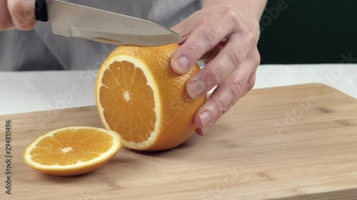 Female hands cut juicy orange on cutting board. Close up