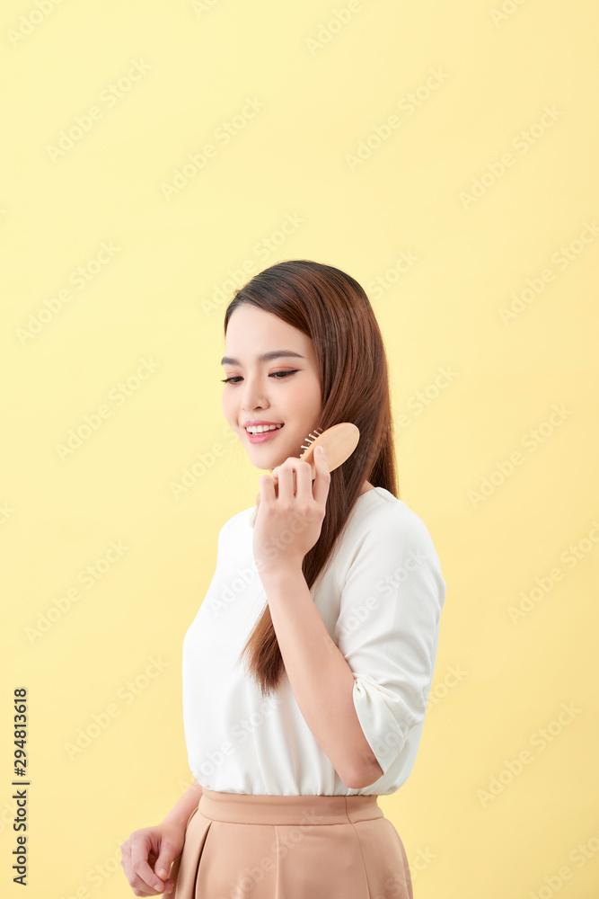 Portrait of beautiful young woman combing her hair and smiling Portrait of beautiful young woman combing her hair and smiling