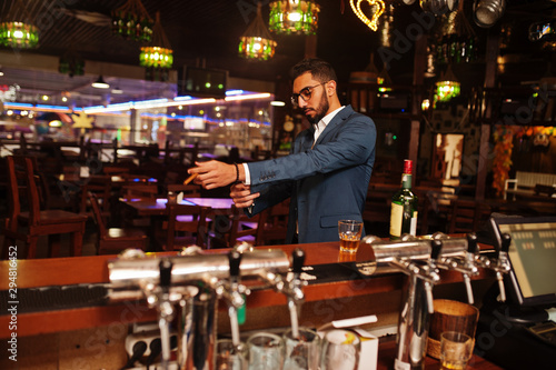 Handsome well-dressed arabian man with glass of whiskey and cigar posed at pub. © AS Photo Family