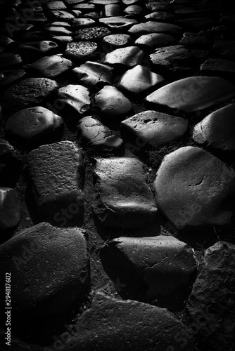 a vintage  roman street as a closeup while the sun is reflectiing in black and white portrait format  photo