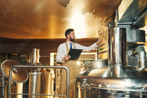 Quadro su tela Handsome engineer of brewery inspecting process of brewing.