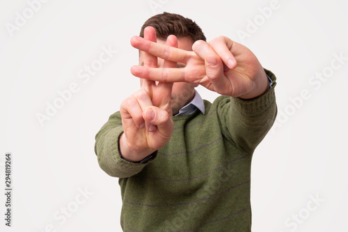 Caucasian man in green sweater standing, showing hashtag. photo