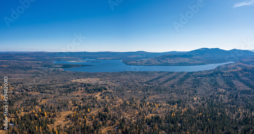 Fototapeta Naklejka Na Ścianę i Meble -  Aerial drone view of Zuratcul lake in autumn surrounded by Ural mountains, hills, mixed forest with green pines and yellow birchs; colorful trees on coasts; fragile ecosystem and anthropogenic impact