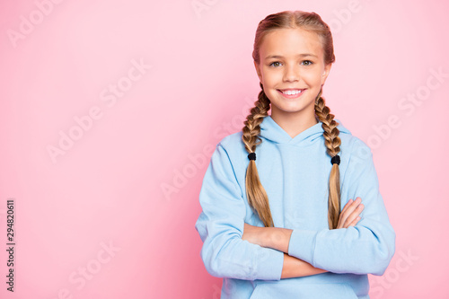 Photo of cheerful positive confident girl of good mood standing confidently with arms crossed showing her intelligence near empty space isolated over pink pastel color background