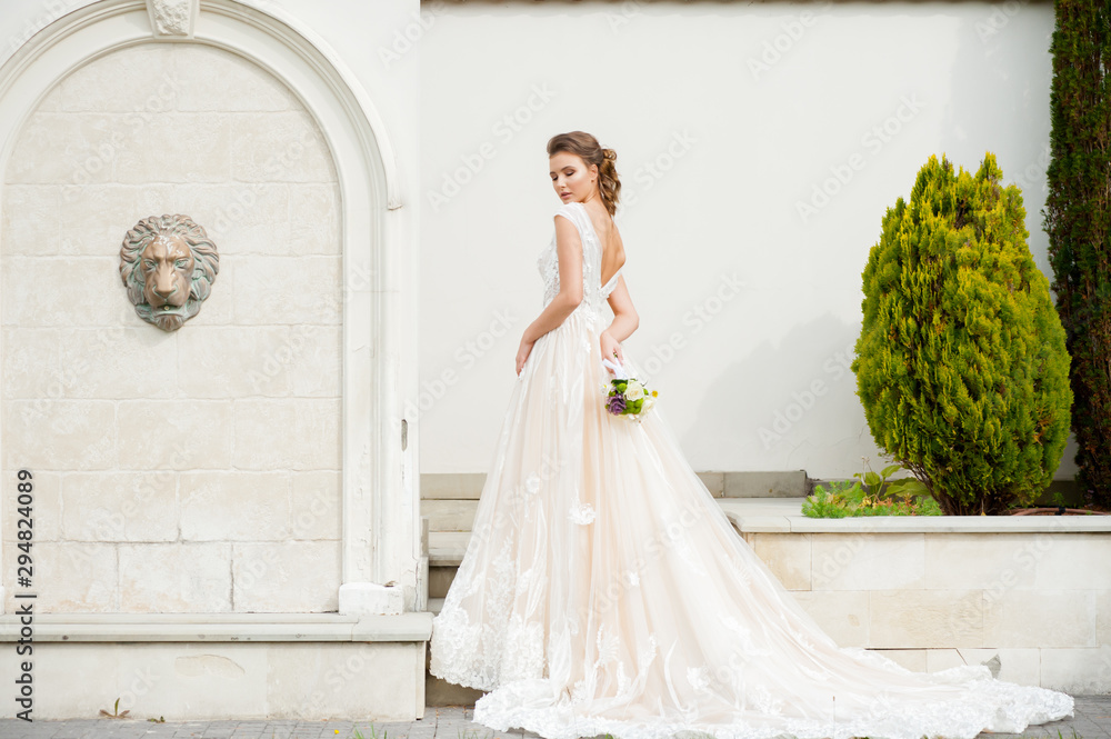Fototapeta premium Bride in long wedding dress with bouquet outdoor