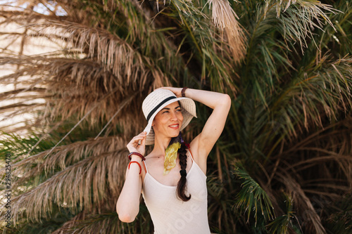 Smiling woman wearing dress standing close to palm tree