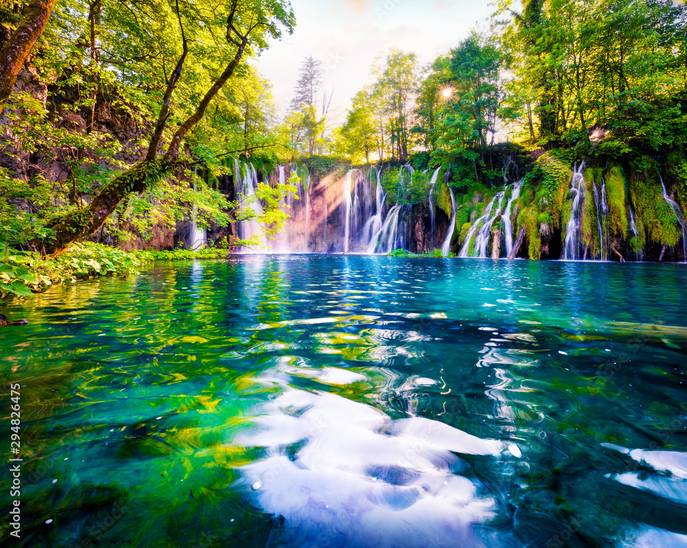 Last sunlight lights up the pure water waterfall on Plitvice National Park. Spectacular spring scene of green forest with blue lake. Wonderful countryside view of Croatia, Europe.