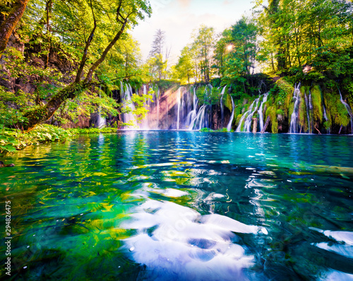 Fototapeta Naklejka Na Ścianę i Meble -  Last sunlight lights up the pure water waterfall on Plitvice National Park. Spectacular spring scene of green forest with blue lake. Wonderful countryside view of Croatia, Europe.
