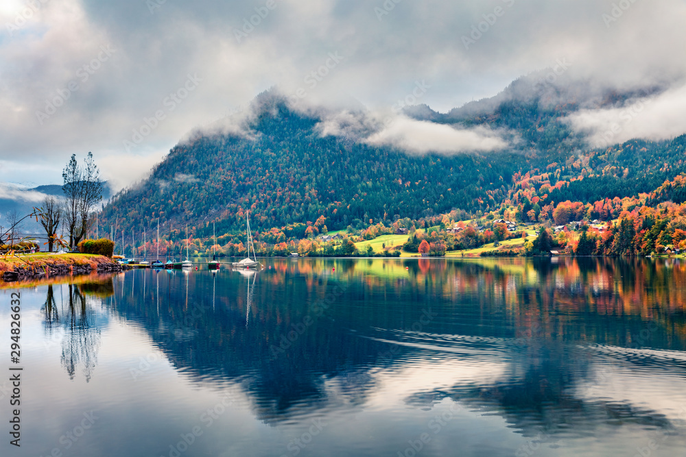 Fototapeta premium Foggy autumn view of Grundlsee lake. Wonderful morning scene of Brauhof village, Styria stare of Austria, Europe. Colorful view of Alps. Traveling concept background.